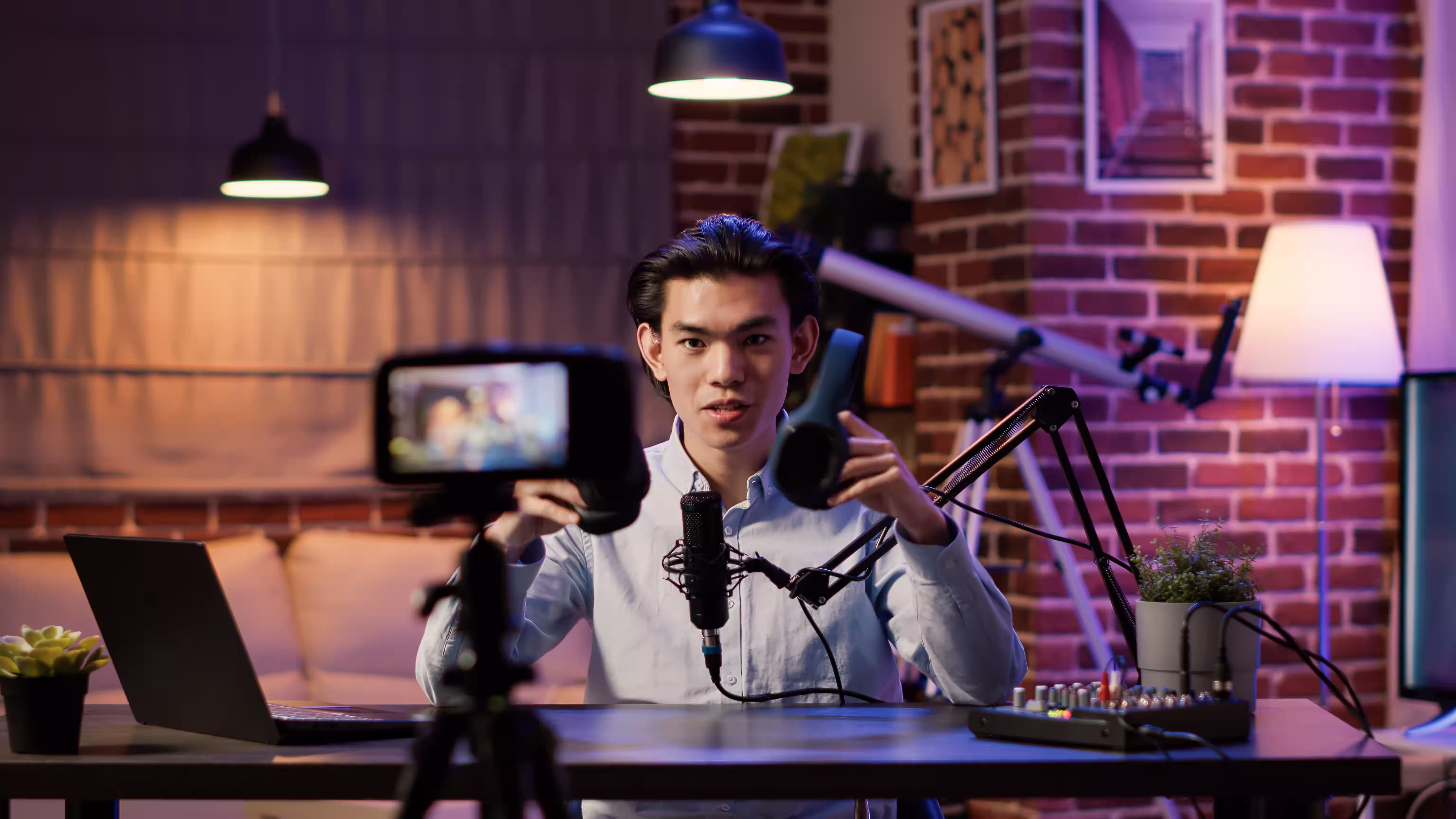 Young man recording podcast in well-designed home studio with microphone boom arm and monitor